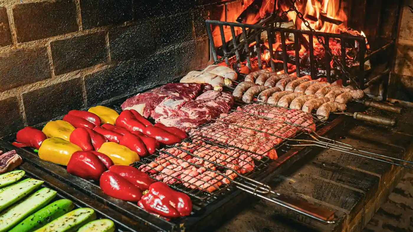 Parrilla uruguaya con carnes, chorizos y verduras sobre las brasas de una chimenea de ladrillo