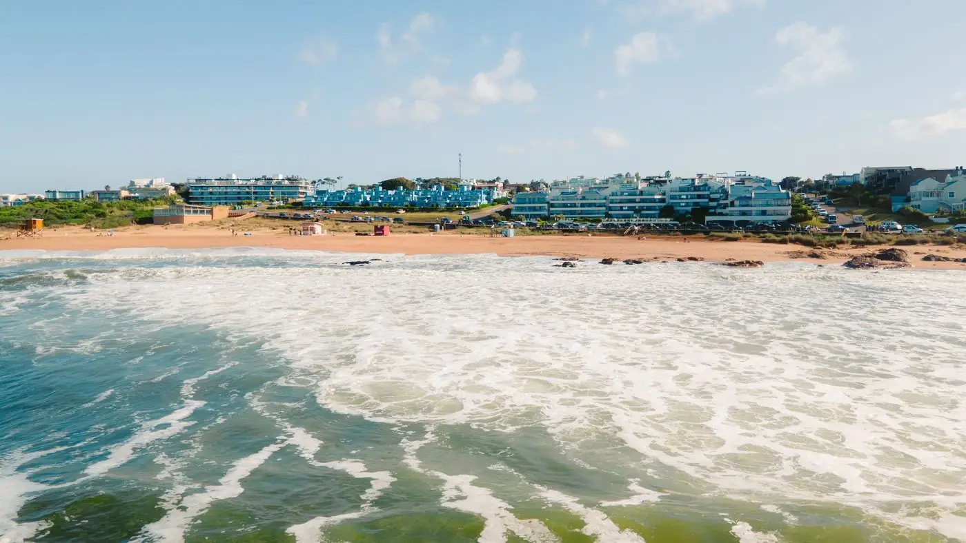 Playa de la costa de Punta del Este en un día de verano, con el oleaje en primer plano y los edificios frente al mar