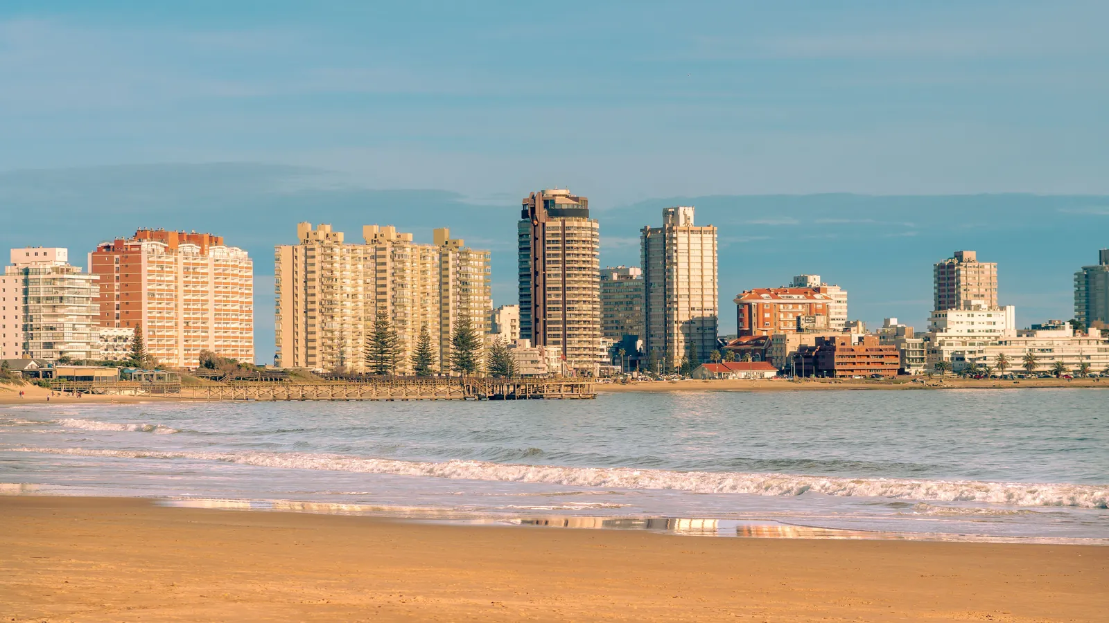 Los edificios de Punta del Este vistos desde la playa a la luz del día, con el muelle y el mar en primer plano