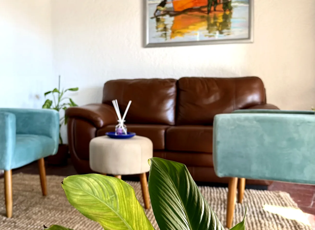 La sala de espera del estudio, con los sillones, el cuadro de la barca y las vigas de madera del techo